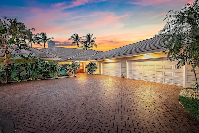 view of front facade with a garage, decorative driveway, and a chimney