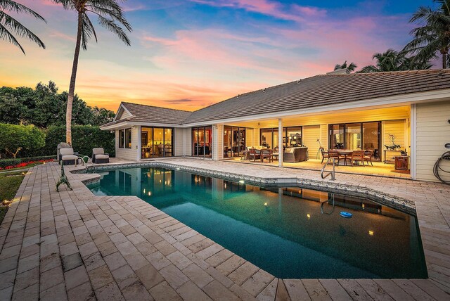 pool at dusk featuring a patio area