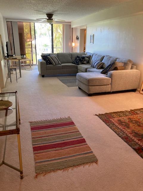 living room featuring a textured ceiling, ceiling fan, and carpet