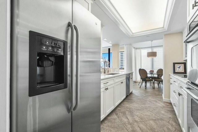 kitchen featuring white cabinetry, appliances with stainless steel finishes, ornamental molding, pendant lighting, and sink