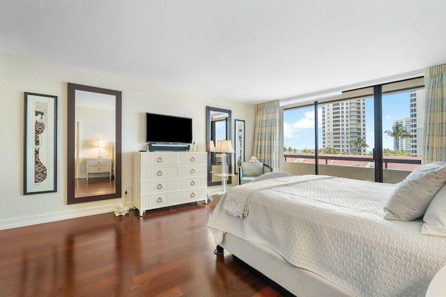 bedroom with a wall of windows and dark hardwood / wood-style floors