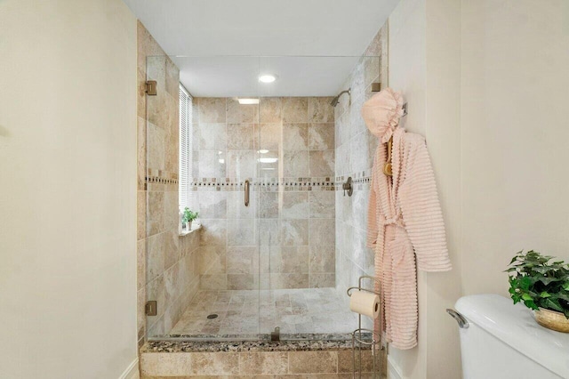 bathroom featuring toilet and a shower with shower door