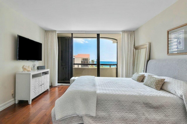 bedroom with dark hardwood / wood-style flooring and a wall of windows