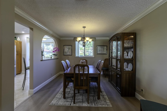 dining room with hardwood / wood-style floors, a notable chandelier, ornamental molding, and a textured ceiling