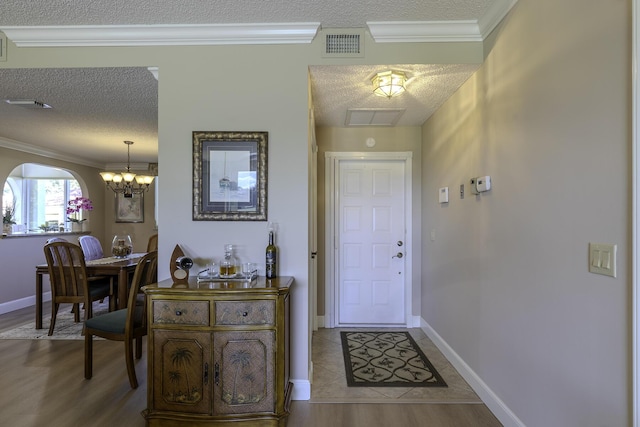 foyer with ornamental molding, a textured ceiling, and a notable chandelier