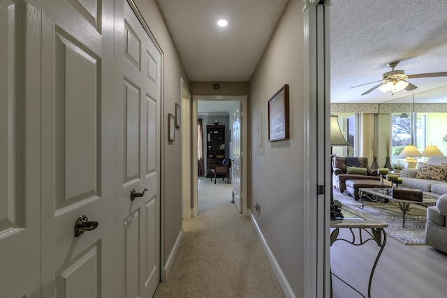 corridor featuring light colored carpet and a textured ceiling