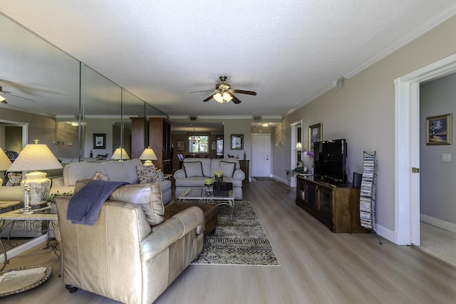 living room with a textured ceiling, light hardwood / wood-style flooring, ceiling fan, and ornamental molding