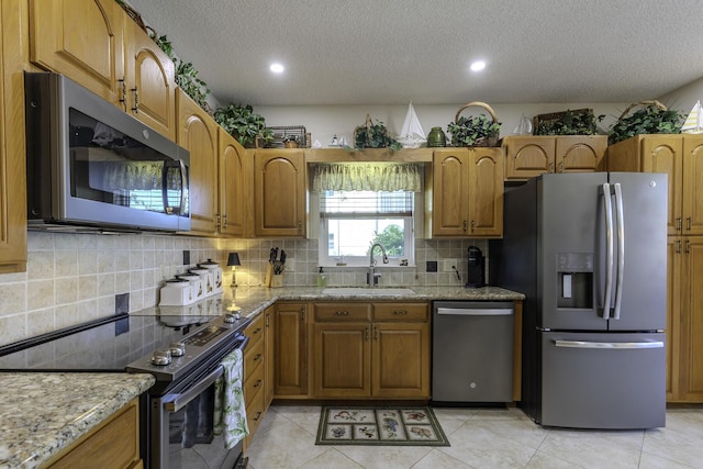 kitchen with appliances with stainless steel finishes, a textured ceiling, light tile patterned floors, and sink