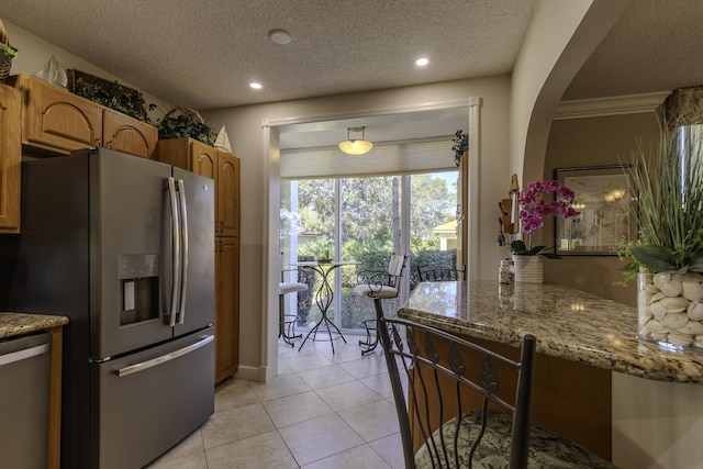 kitchen featuring crown molding, light tile patterned floors, a textured ceiling, and appliances with stainless steel finishes