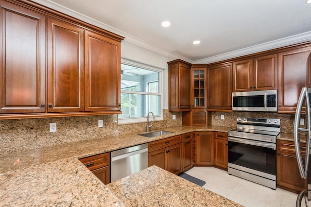 kitchen with sink, light tile patterned floors, light stone countertops, appliances with stainless steel finishes, and ornamental molding