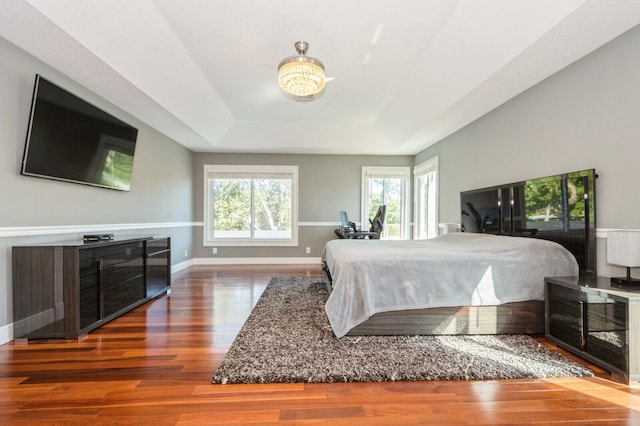 bedroom featuring a tray ceiling, a notable chandelier, and hardwood / wood-style flooring