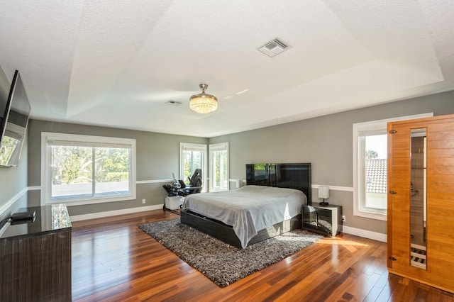 bedroom with hardwood / wood-style floors, a textured ceiling, and a raised ceiling