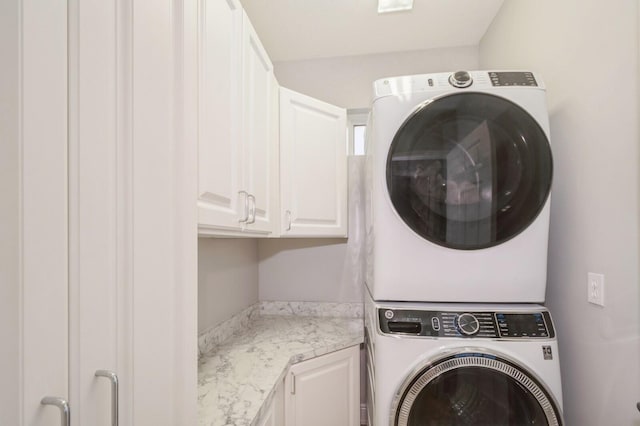 laundry room featuring cabinets and stacked washing maching and dryer