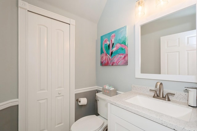 bathroom with toilet, vanity, and vaulted ceiling