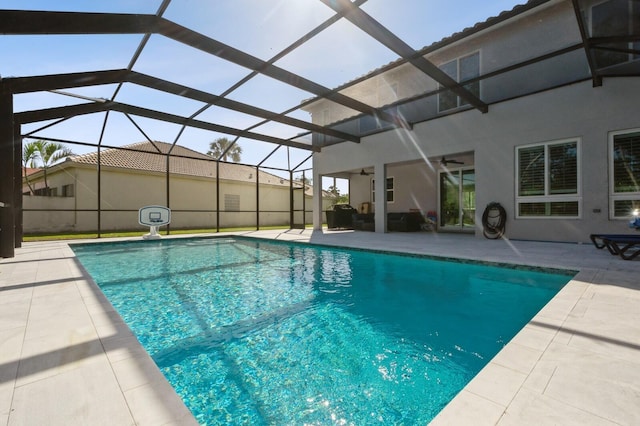 view of swimming pool with glass enclosure, ceiling fan, and a patio area