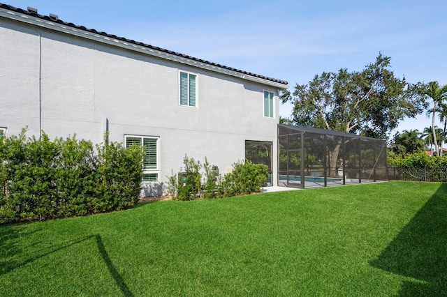 rear view of house featuring a lanai and a lawn