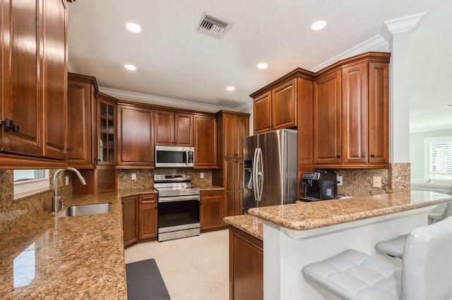 kitchen featuring kitchen peninsula, a kitchen breakfast bar, tasteful backsplash, stainless steel appliances, and sink