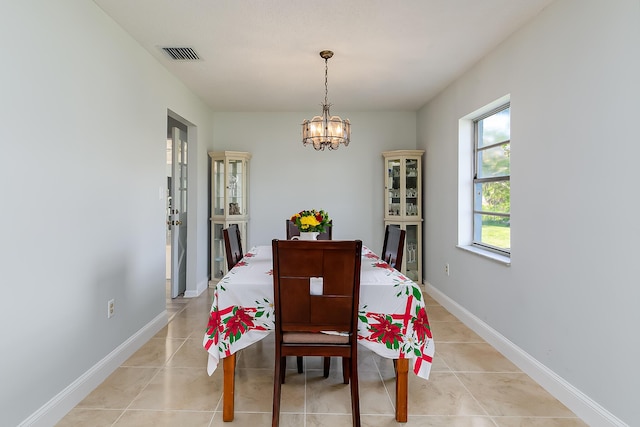 tiled dining room with an inviting chandelier