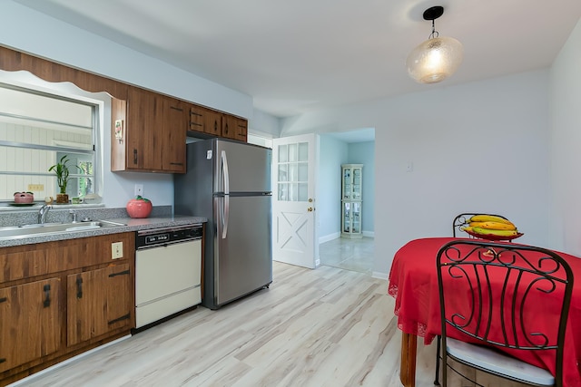 kitchen with dishwasher, sink, stainless steel fridge, light hardwood / wood-style floors, and decorative light fixtures