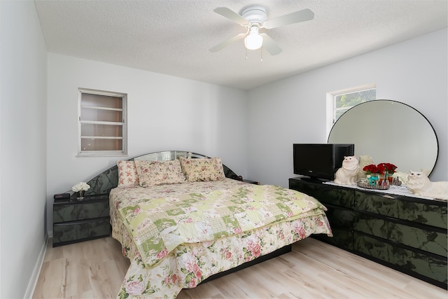 bedroom with ceiling fan, light wood-type flooring, and a textured ceiling