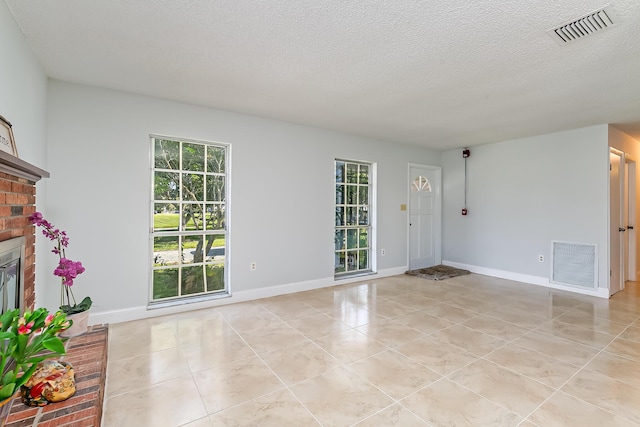 unfurnished living room with light tile patterned flooring, a textured ceiling, and a brick fireplace