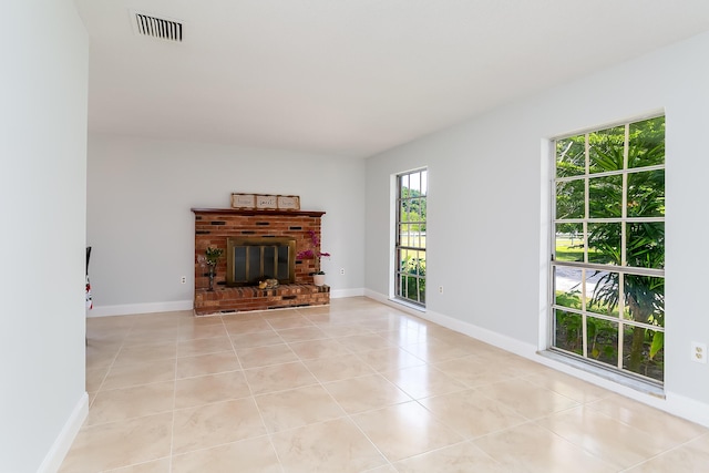 unfurnished living room featuring light tile patterned floors and a brick fireplace