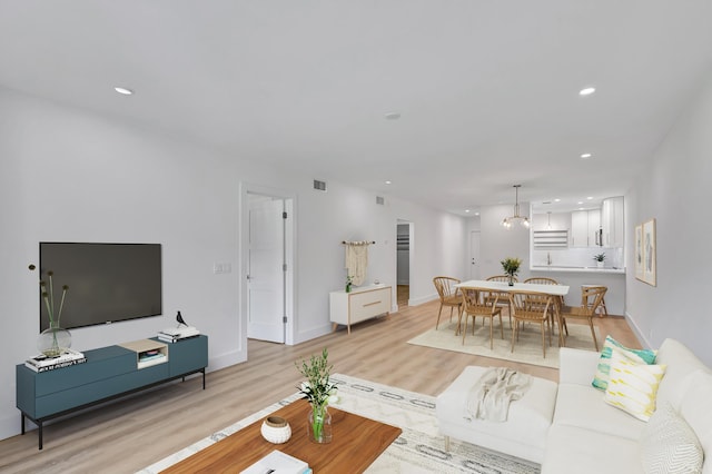 living room featuring light wood-type flooring and an inviting chandelier