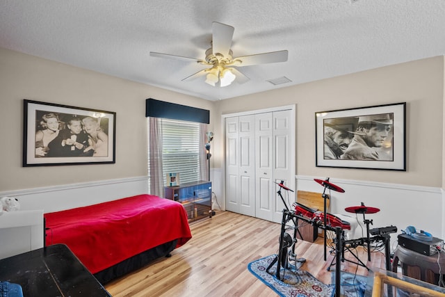 bedroom with ceiling fan, a closet, a textured ceiling, and hardwood / wood-style flooring