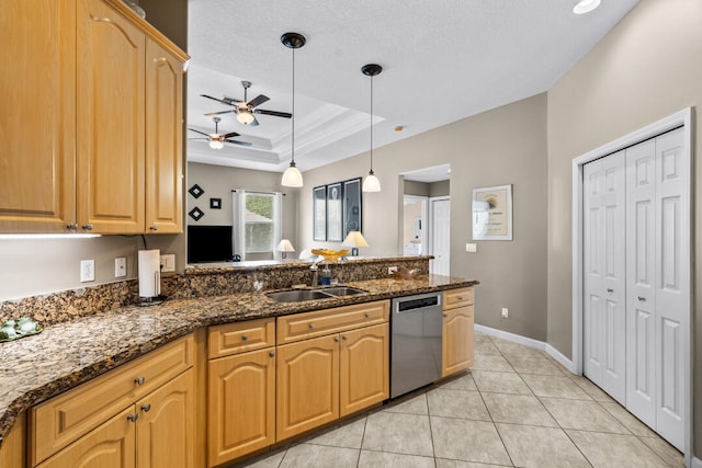 kitchen with pendant lighting, dishwasher, a raised ceiling, sink, and dark stone countertops