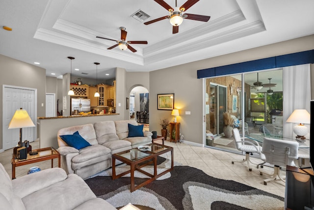 living room with a tray ceiling, light tile patterned floors, and ornamental molding