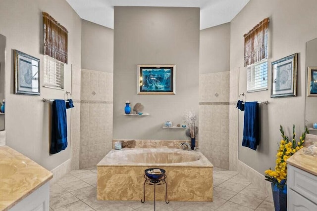 bathroom featuring a washtub, vanity, tile patterned floors, and tile walls