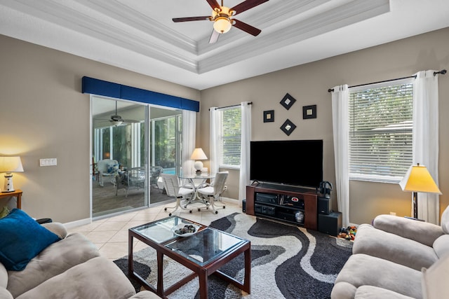 living room featuring ceiling fan, light tile patterned floors, ornamental molding, and a tray ceiling