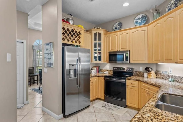 kitchen with light brown cabinets, sink, light stone countertops, light tile patterned flooring, and stainless steel appliances