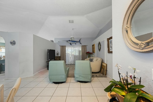 living room featuring ceiling fan, light tile patterned floors, vaulted ceiling, and a textured ceiling