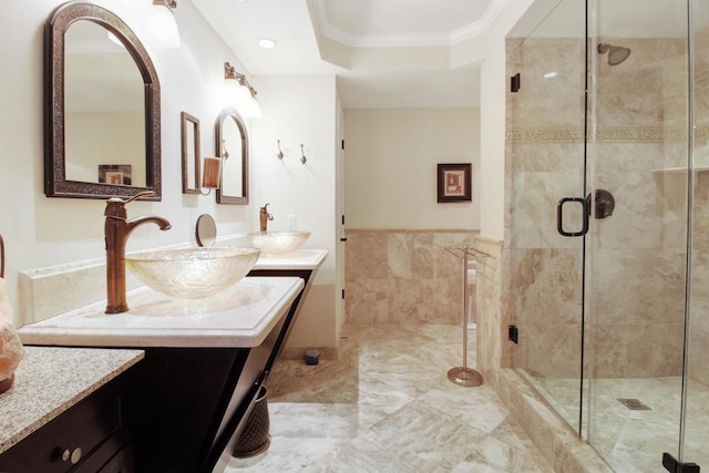 bathroom featuring vanity, a shower with shower door, tile walls, and ornamental molding