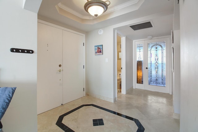 entryway with ornamental molding and a tray ceiling