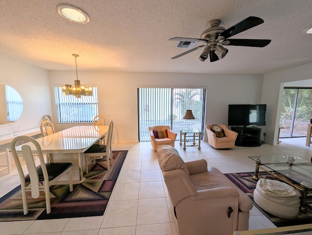 tiled living room featuring a textured ceiling and ceiling fan with notable chandelier