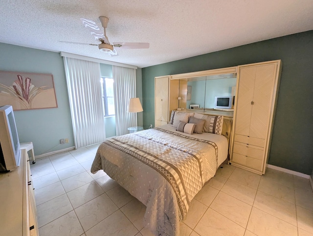 bedroom featuring ceiling fan, light tile patterned flooring, and a textured ceiling