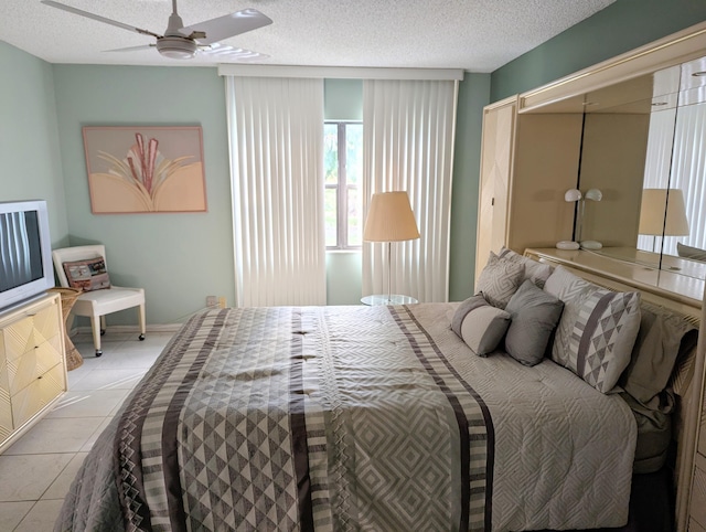 bedroom with ceiling fan, light tile patterned floors, and a textured ceiling