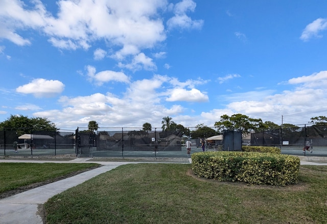 view of property's community featuring a yard and tennis court