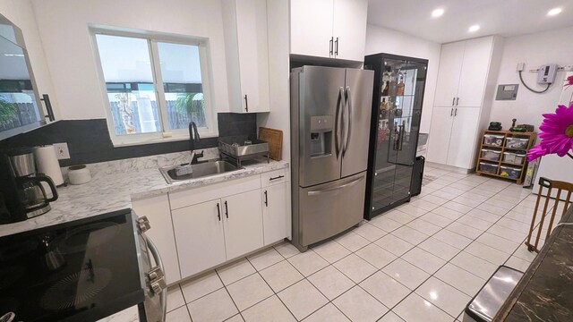 kitchen featuring sink, white cabinets, stainless steel fridge, stove, and light tile patterned floors