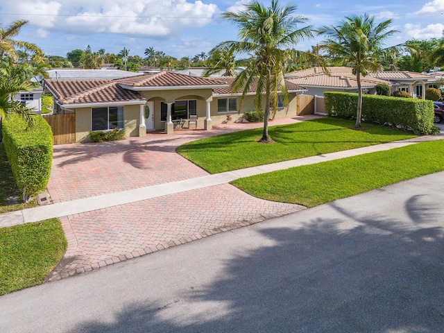 mediterranean / spanish-style home with a front yard and covered porch