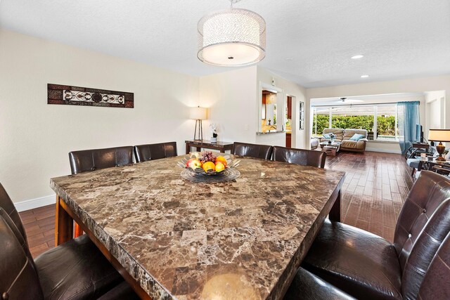 dining room with ceiling fan, dark wood-type flooring, and a textured ceiling