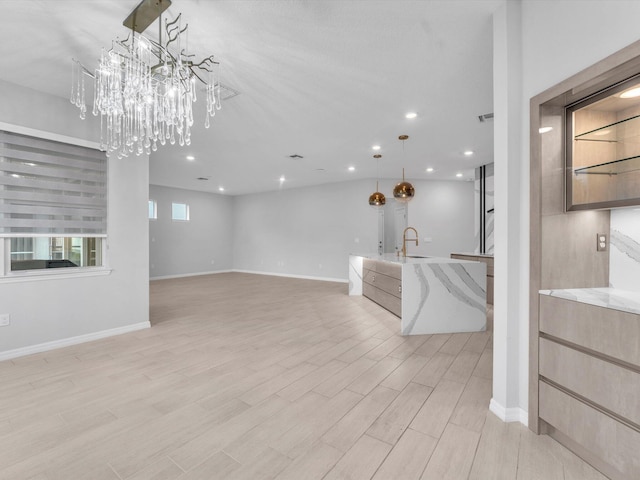 unfurnished living room with a chandelier, light hardwood / wood-style floors, and sink