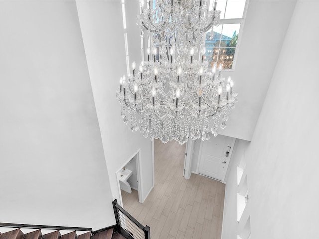 interior space featuring light wood-type flooring, a chandelier, and a high ceiling