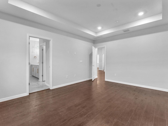 empty room with a raised ceiling and dark hardwood / wood-style floors