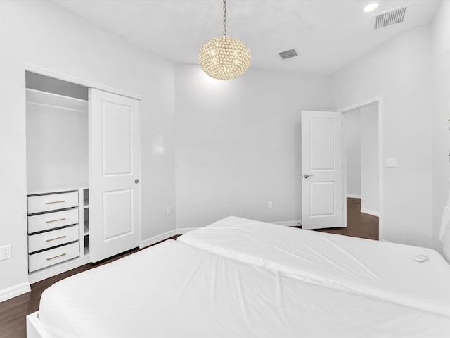 bedroom featuring a closet, dark hardwood / wood-style floors, and an inviting chandelier