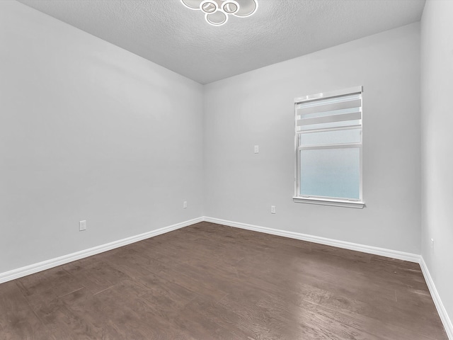 unfurnished room featuring a textured ceiling and dark hardwood / wood-style flooring