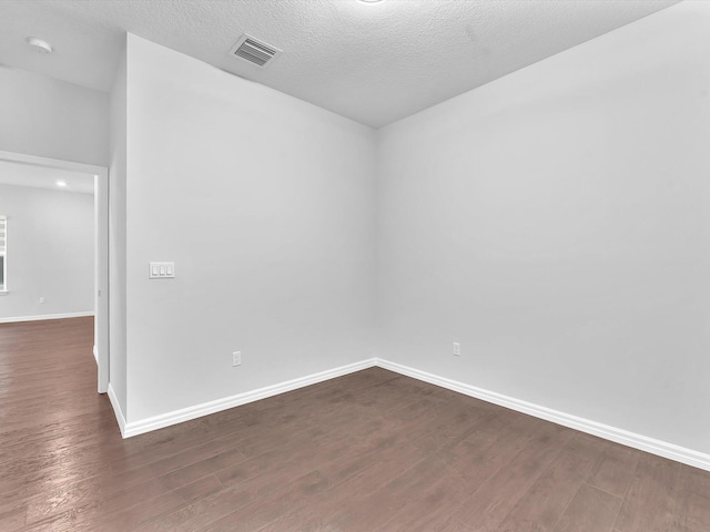 unfurnished room with a textured ceiling and dark hardwood / wood-style flooring