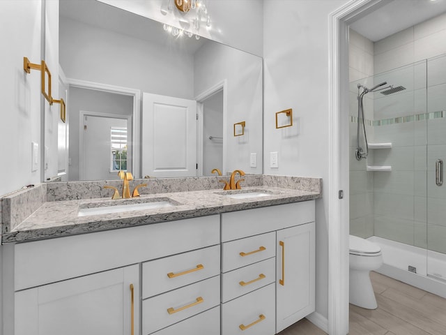 bathroom featuring toilet, vanity, wood-type flooring, and an enclosed shower